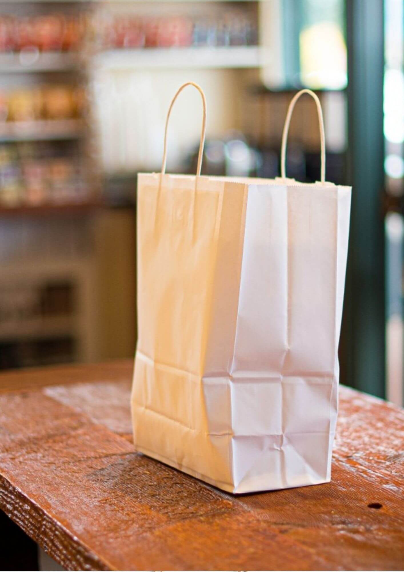 A brown kraft paper bag on a wooden counter in a retail shop